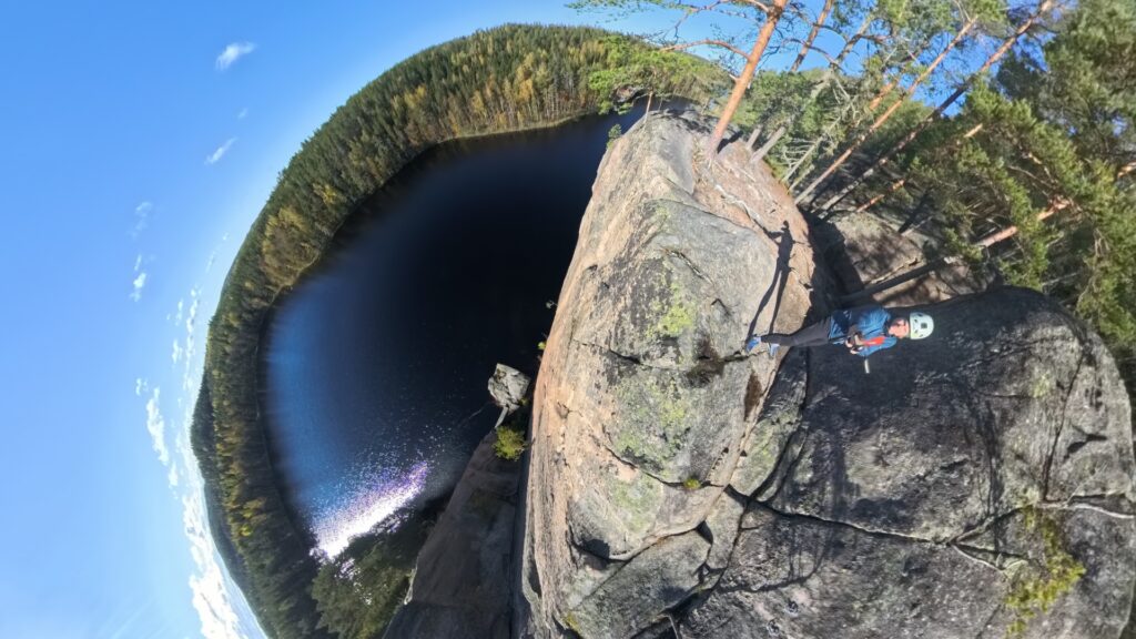 360-laajakuva kallion huipulta järven vierellä. Kuvaaja seisoo kallion reunalla.